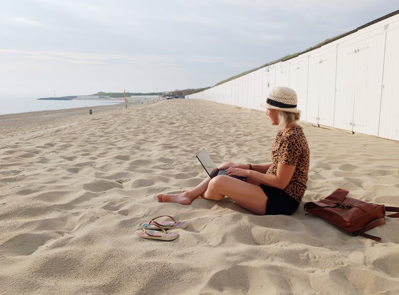 Vrouw aan het werk op de laptop met het strand als decor