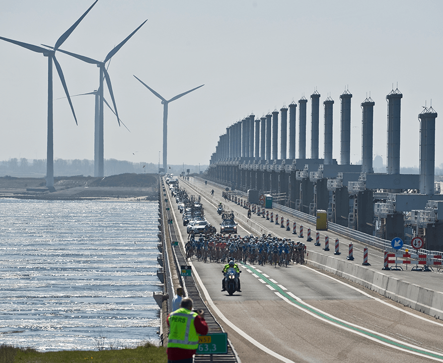 Het wielren peleton fietst over de Oosterscheldekering, ofwel stormvloedkering