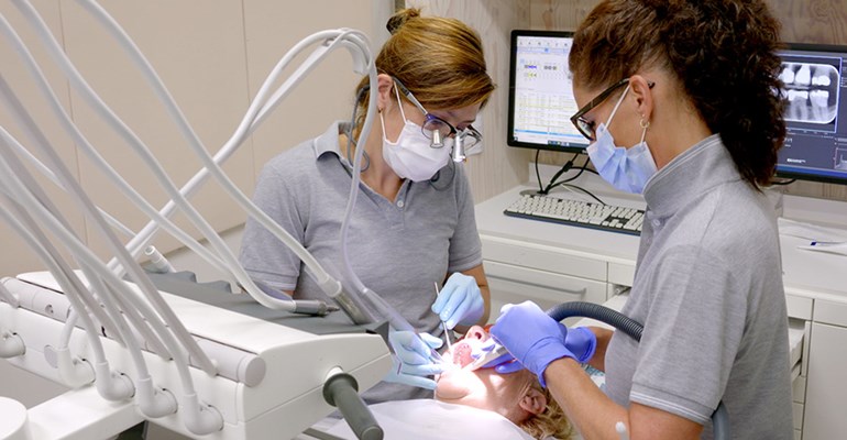 Tandarts en tandartsassistente voeren periodieke controle uit bij patiënt in tandartspraktijk in Zeeland