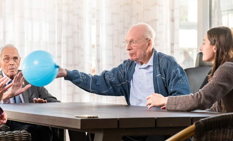 Ouderen spelen met een balon aan tafel