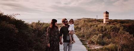 Zonsondergang in de duinen met familie op de voorgrond en op de achtergrond de zee en strand dishoek