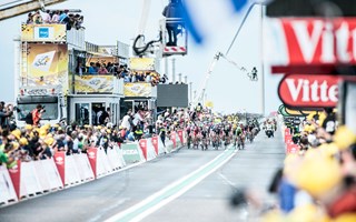 Wielrenners gaan finishen op de Oosterscheldekering tijdens de Tour de France, honderden mensen staan de wielrenners aan te moedigen