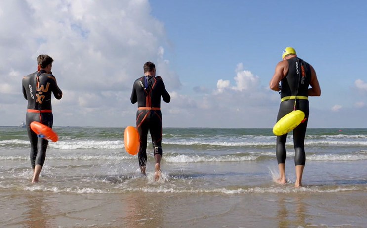 Vier personen met duikpak aan gaan zwemmen aan de zee in Vlissingen