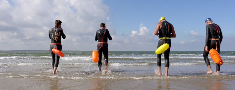 Vier personen met duikpak aan gaan zwemmen aan de zee in Vlissingen
